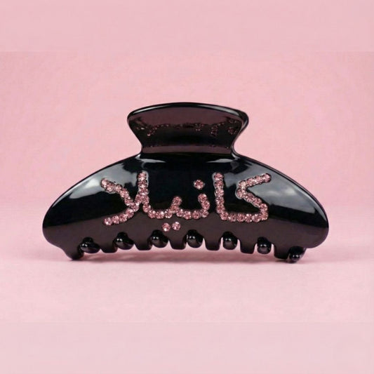 Black acetate claw clip with custom pink crystals in Arabic script spelling Kanella